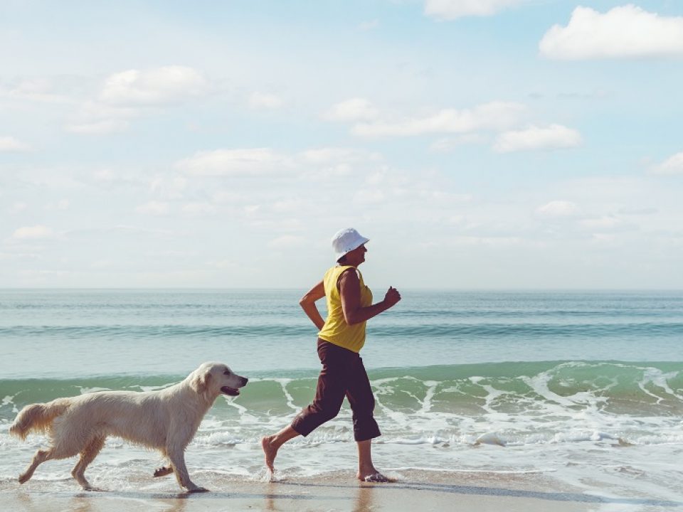 woman and dog jogging on beach
