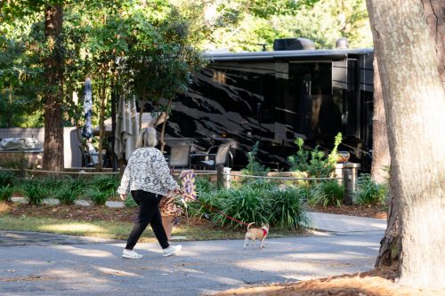 Woman walking a small dog past a motorcoach site at Hilton Head Island Motorcoach Resort