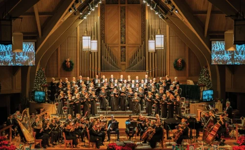 Orchestra and choir performing a holiday concert with Christmas trees on stage